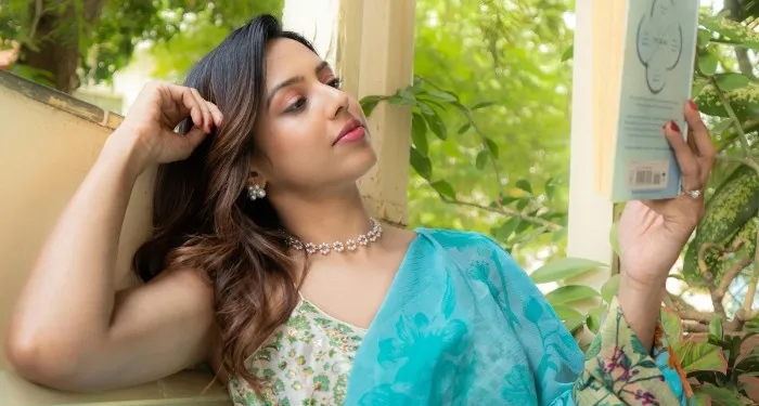 a woman with light brown skin wearing a sari reading on a patio